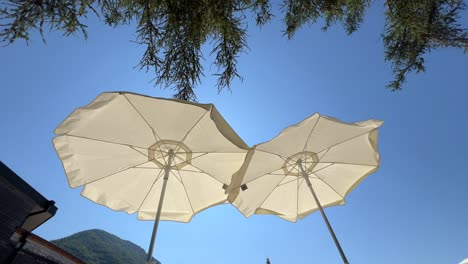 Dos-Sombrillas-De-Playa-Con-Cielo-Azul-De-Fondo