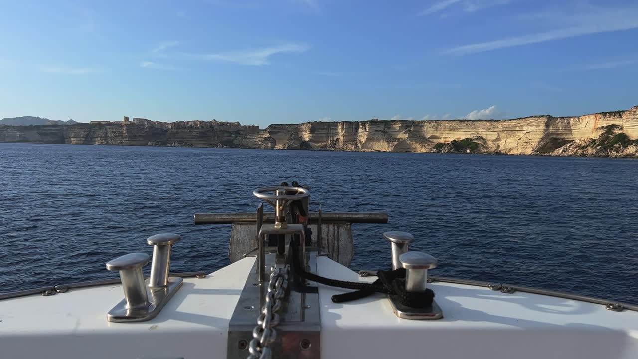 vista en primera persona de la proa del velero que avanza navegando hacia la ciudad de bonifacio en la cima de altos acantilados en córcega, francia