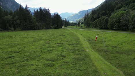 drone push in: green valley and small path next to fir forest in the swiss alps, obwalden, engelberg aerial view