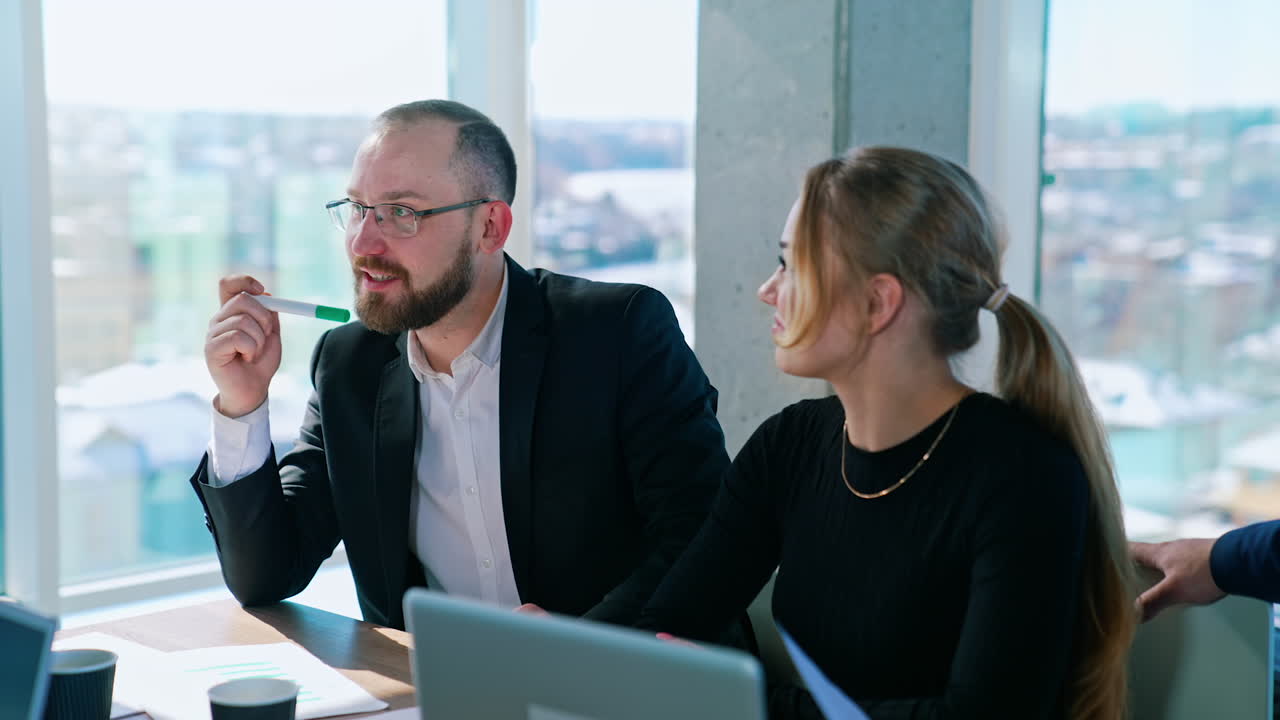 Partners for business indoors. Businessman and beautiful woman sitting together at the table in office room. Business meeting concept.