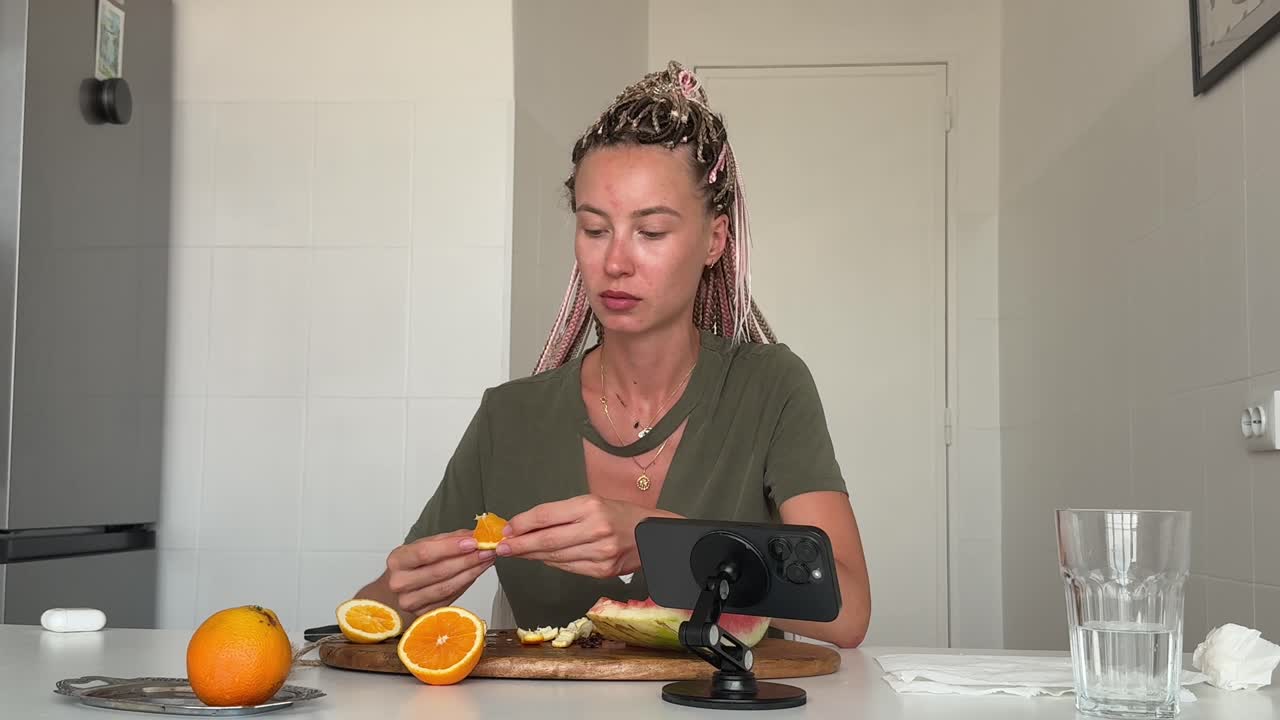 Young Woman Eating and Peeling Fresh Orange in Kitchen