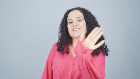 Happy-young-woman-waving-at-camera.