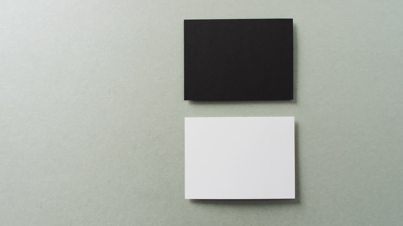 acercamiento de dos pilas de tarjetas de visita en blanco y negro sobre fondo gris, espacio de copia, cámara lenta