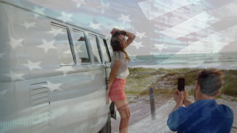 animation of waving flag of usa over couple having fun on the beach