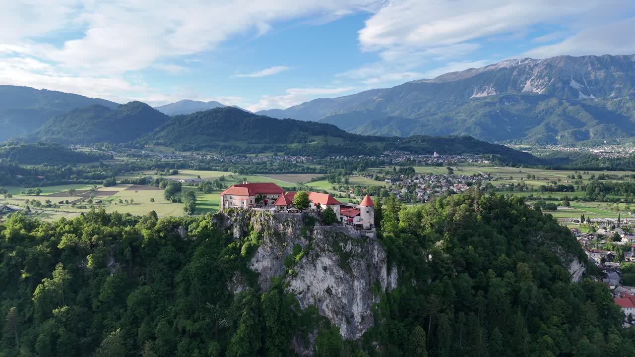 Drone trekker seg tilbake fra Bled slott og avslører klippe, innsjø, fjell og by