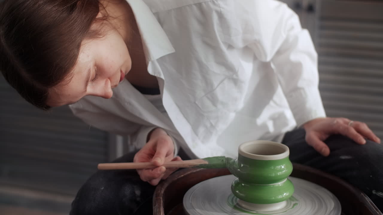 Woman painting a ceramic piece on a pottery wheel