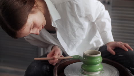 woman painting a ceramic piece on a pottery wheel