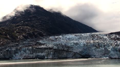 cloud covered mountain and a glacier in glacier bay national park, alaska