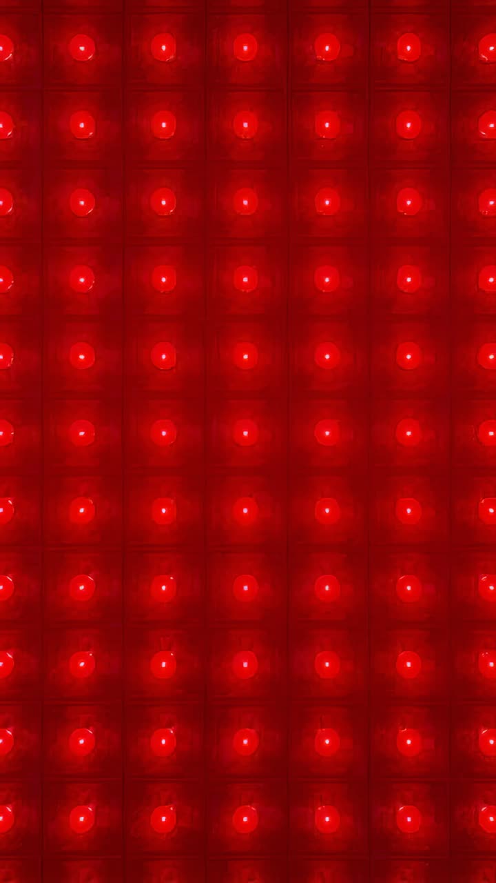 Vertical video: Powering LED panel cycling light against wall, with grid diodes shifting color