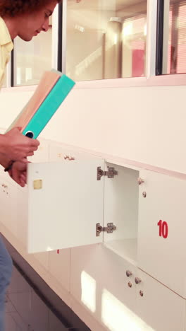 handsome student putting notebooks in his locker