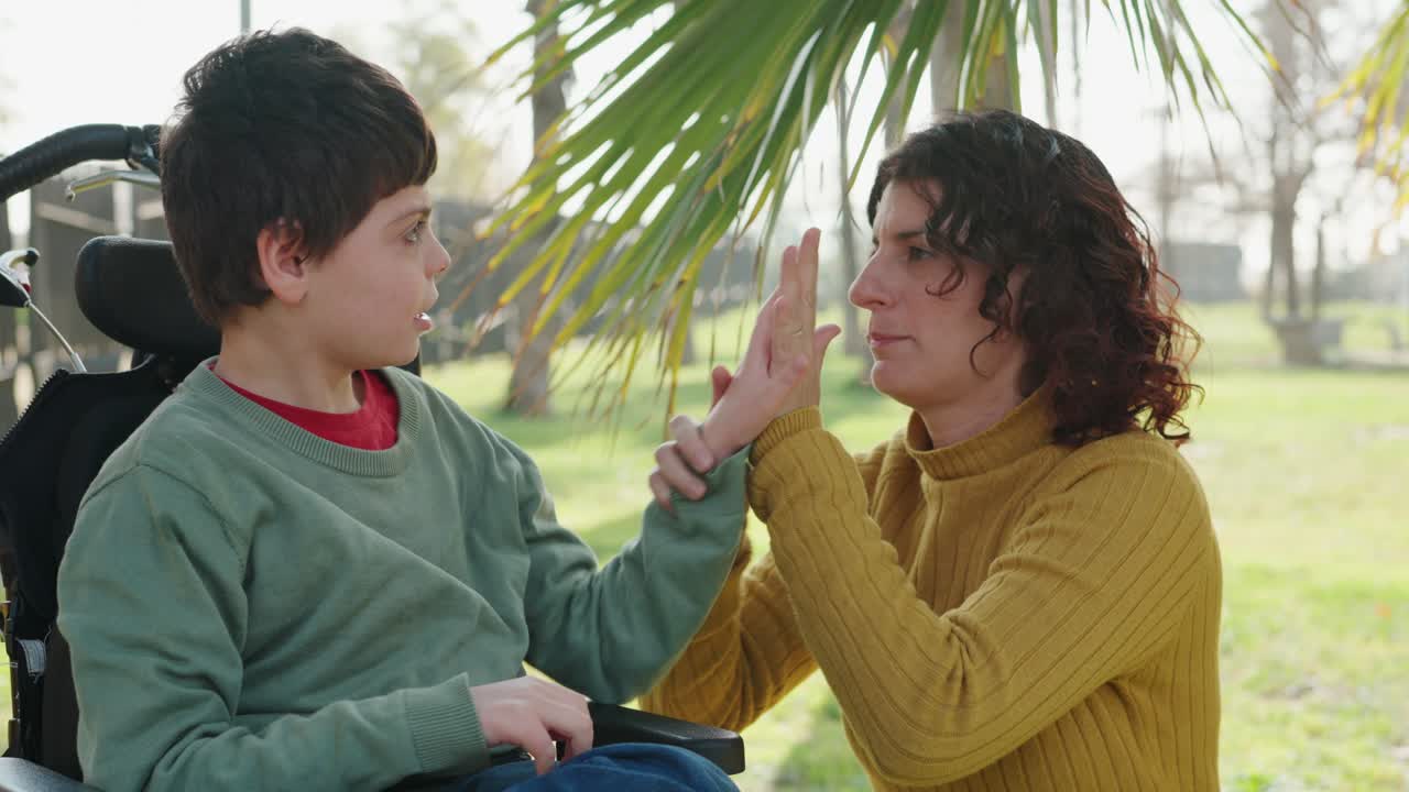 A touching moment between a child in a wheelchair and a caring woman in a park