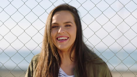 A-cheerful-young-woman-standing-by-a-fence