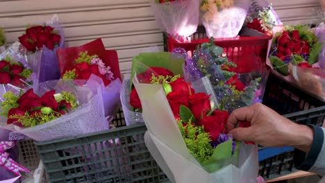 un vendedor prepara ramos de rosas de pétalos rojos para la venta mientras quita los pétalos de las rosas en el mercado de flores durante el día de san valentín
