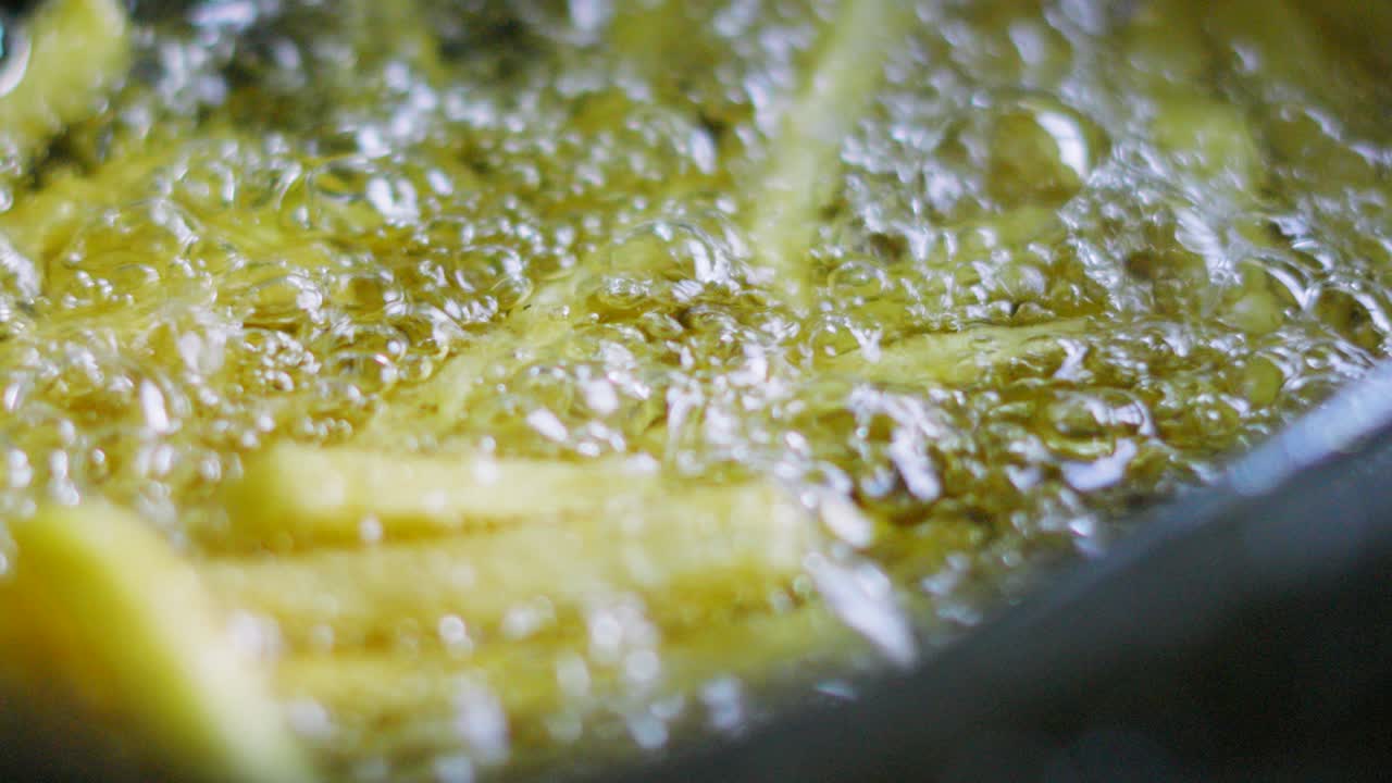 Bubbling Hot Oil Cooking French Fries in Deep Fat Fryer in Slow Motion. Unhealthy Fast Food Chips