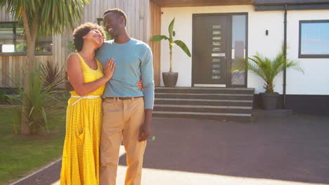 portrait of couple standing in driveway in front of dream home together