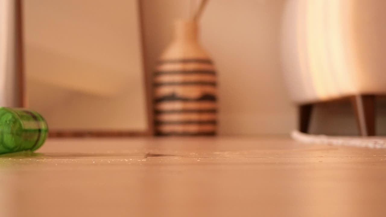 Green bottle on a light brown floor in a room