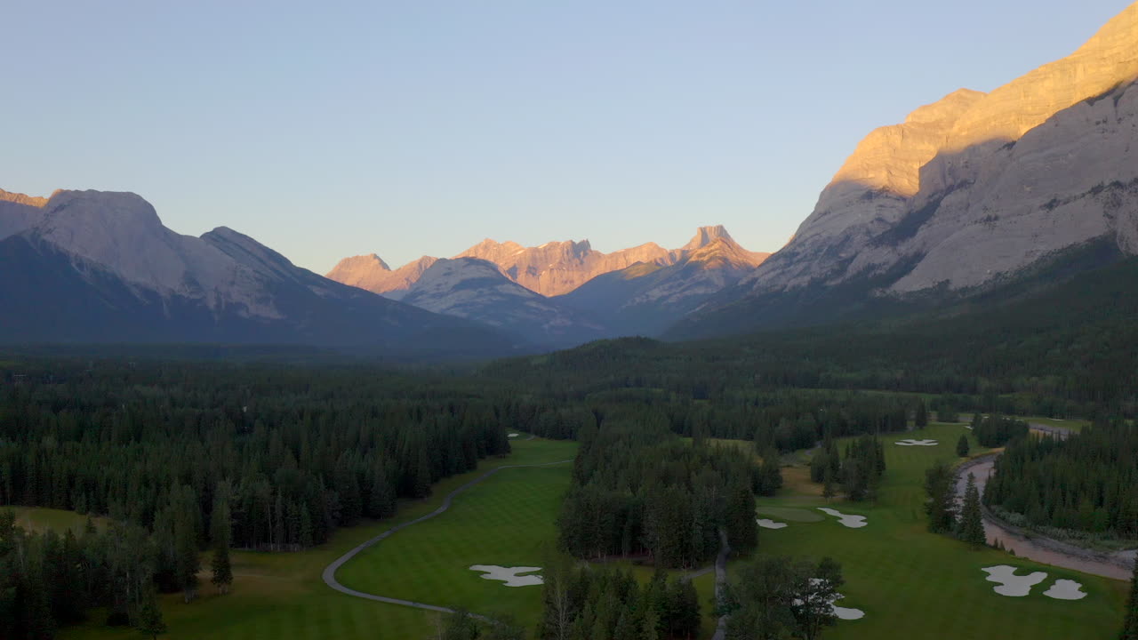 vista aérea de drones del campo de golf verde con brillo alpino en las montañas rocosas de banff y kananaskis de alberta, canadá al amanecer