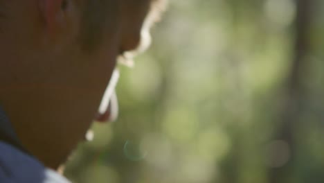 close up of a man as he walks through a forest