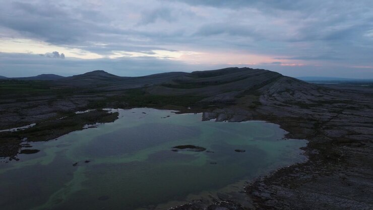 Il crepuscolo proietta una luce soffusa su acque calme e terreno accidentato nella Contea di Clare. Ideale per documentari paesaggistici o servizi di viaggio
