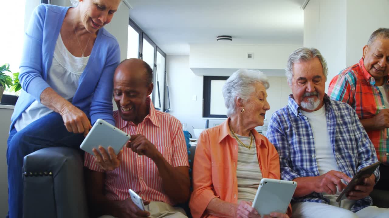 Amigos idosos felizes usando tablet digital no sofá