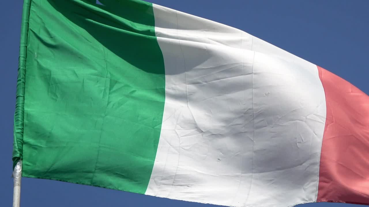 4K. Italian flag waving in the wind on a blue sky. Italy flag