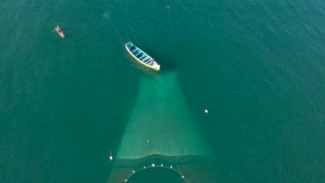 Vista-Aérea-De-Arriba-Hacia-Abajo-Del-Barco-De-Pescadores-Con-La-Red-De-Pesca-Colocada-Sobre-La-Superficie-Del-Agua-Para-Pescar