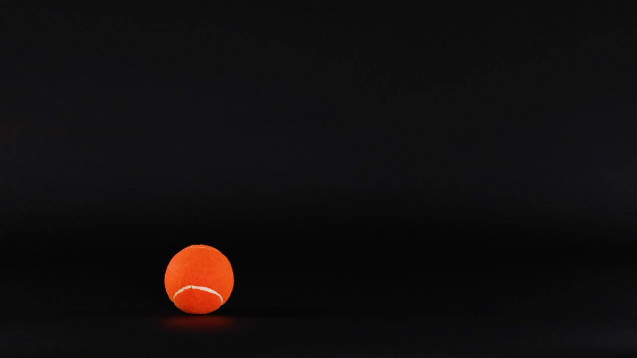 una pelota de tenis rodando sobre un fondo oscuro