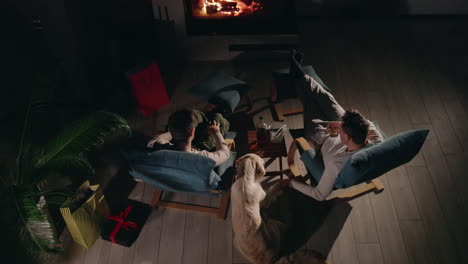 friends relaxing by the fireplace with gifts and a dog