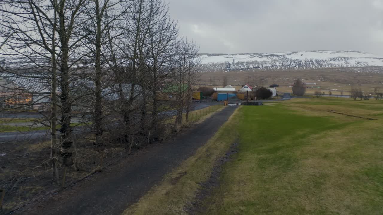 Aerial View of Serene Road Leading to Snow-Covered Mountains in Small Town in Iceland