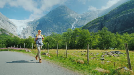 una mujer activa y exitosa viaja a través de noruega camina con el telón de fondo de las montañas con un bac