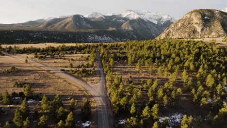 Drone-retreating-from-Mount-Antero-down-a-lonely-road-with-pine-trees-on-both-sides-during-sunset