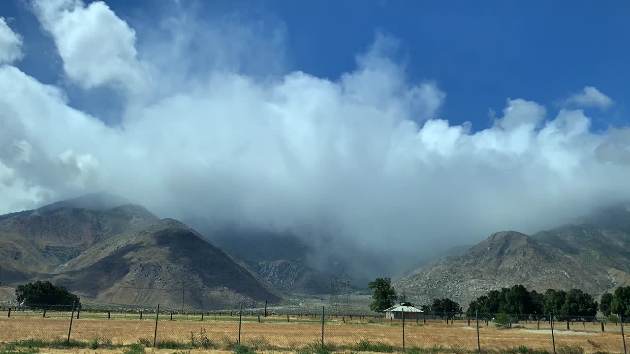 paisaje de montaña rural de 4k timelapse con nubes que soplan que fluyen dramáticamente a través de un cielo azul y sobre la montaña