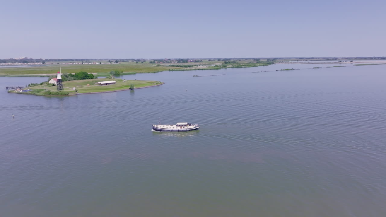 The Luxemotor boat navigates through the peaceful landscape of Flevoland, framed by clear skies