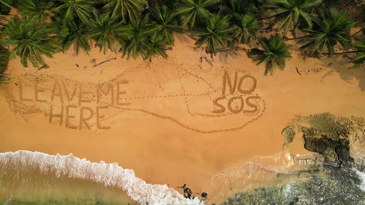 Aerial view of a desert beach with funny inscriptions in the sand saying Leave me Here and No Sos in São Tomé,Africa. Descendig drone shot