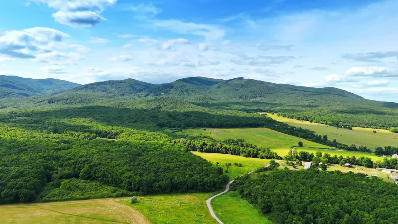Green hills in Europe. Expansive view of green hills and fields in Europe under a clear blue sky on a sunny day, showcasing nature's beauty