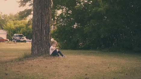 una chica joven come yogur con una cuchara grande sentada en un árbol