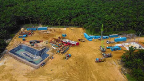 Cinematic-Drone-Footage-of-Onshore-Drilling-Rig-equipment-structure-for-oil-exploration-and-exploitation-in-the-middle-of-jungle-surrounded-by-palm-oil-trees-during-sunset-and-high-oil-price