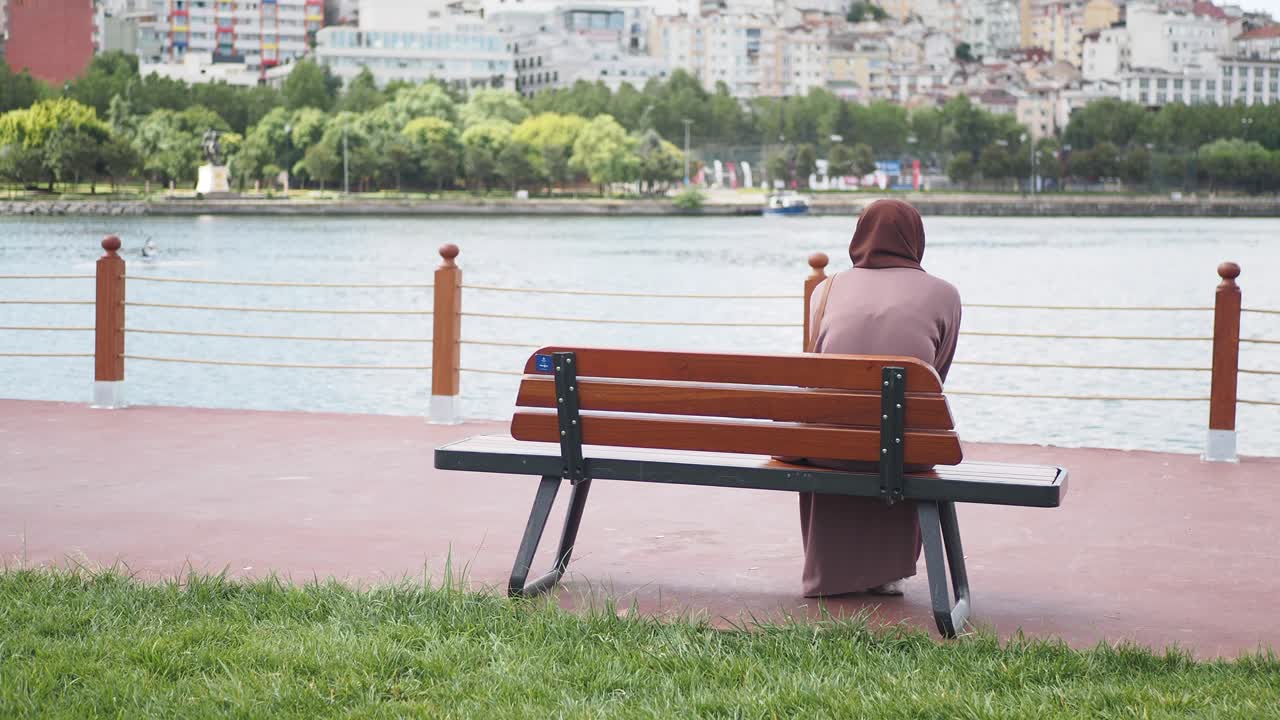 도시 공원 에 있는 강  의 벤치 에 앉아 있는 여자