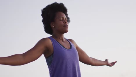 happy african american woman with arms wide on sunny beach