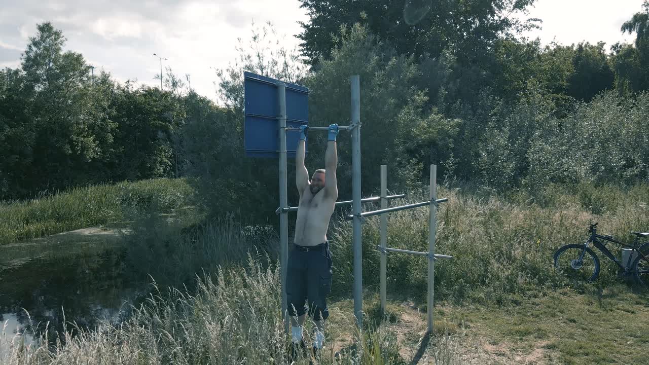 Man Doing Pull Ups On The M50 Sign Next To Grand Canal In Dublin, Ireland On A Sunny Day- Medium Panning Shot