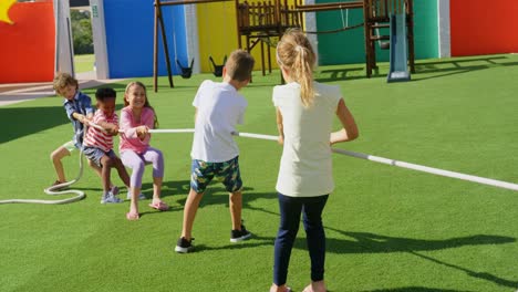 Vista-Trasera-De-Escolares-De-Raza-Mixta-Jugando-Al-Tira-Y-Afloja-En-El-Patio-De-La-Escuela-4k