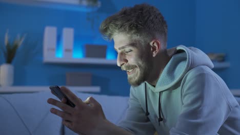 un joven feliz y enamorado enviando mensajes de texto con su novia por teléfono.