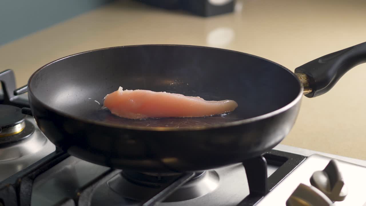 Nærbillede i slow motion af rå kylling placeret på grill-stegepande, der tilberedes på gaskomfur, olie og røg, varme, køkken, restaurant, mad 4K