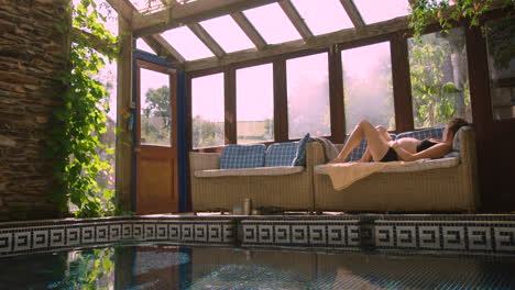 a heavily pregnant woman sleeps by a pool in the sun