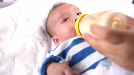 mother giving baby bottle with milk, video in 4k