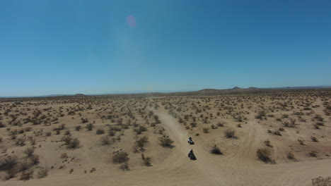 riding four-wheelers in the mojave desert's rugged terrain and harsh climate - aerial first person view in slow motion