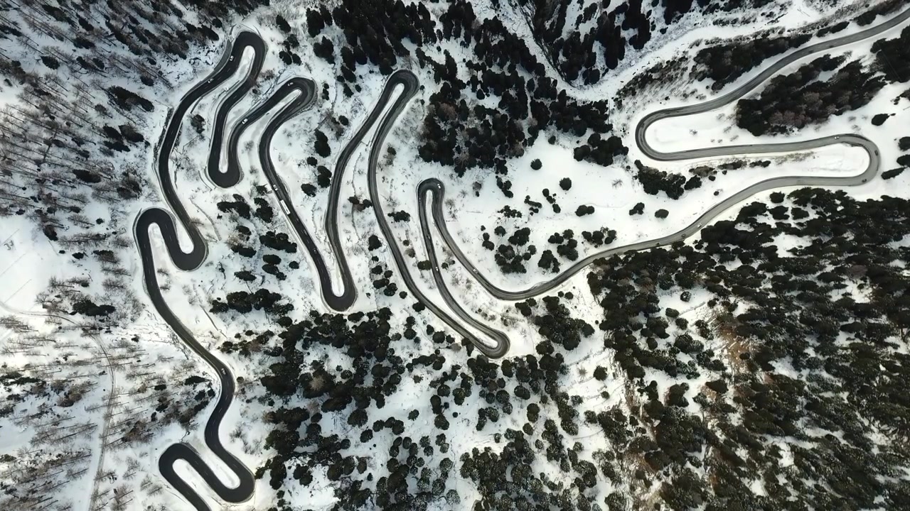 drone overhead shot of traffic circulating in snowy maloja pass in switzerland, showcasing winding road through winter landscape in Graubünden, Switzerland, Europa