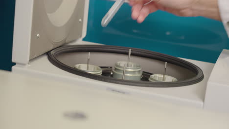 primer plano de científico poniendo muestras de investigación de tubos de ensayo en equipos centrífugos en laboratorio de ciencias, 4k