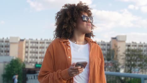 mujer negra caminando a través del puente y mirando su teléfono móvil