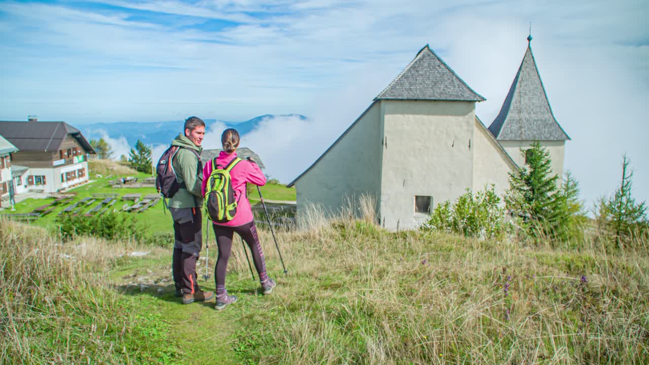 young couple hikers start the way down to a small settlement . Dolly in